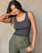 A woman wearing a gray ribbed tank top and green shorts.