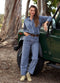 Woman in blue outfit standing next to a green jeep in a natural setting