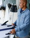 Kelly Slater adjusting fins on a surfboard in a workshop setting